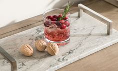 a glass filled with fruit and nuts sitting on top of a marble tray next to a metal holder