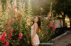 a beautiful young woman standing in front of flowers