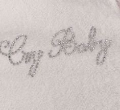 a white shirt with the word baby spelled in silver sequins on it's chest