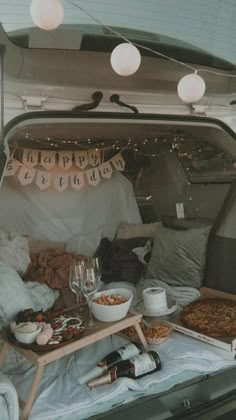 an open trunk filled with food and drinks on top of a bed covered in blankets