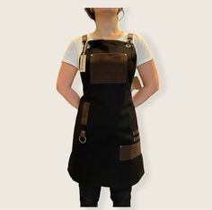 a woman with her hands on her hips wearing a black apron and brown bib