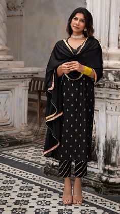 Bring on the festive spirit with our silk kurta set Made in woven silk with golden zari Fully lined kurta and pants Dupatta made in Chiffon with Gota border Color : Black + Gold Model height is 5.6” and is wearing a size M Wash Care : Dry Clean Only Slub Silk Palazzo Set With Traditional Drape For Celebrations, Festive Bollywood Slub Silk Palazzo Set, Festive Gold Slub Silk Palazzo Set, Black Cotton Silk Kurta For Festive Occasions, Traditional Slub Silk Palazzo Set For Celebration, Black Churidar With Cutdana For Festive Occasion, Black Cutdana Churidar For Festive Occasions, Festive Black Cotton Silk Kurta, Black Palazzo Set With Gota Work For Eid