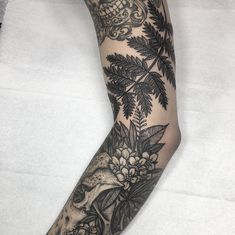 a woman's leg with tattoos and flowers on it