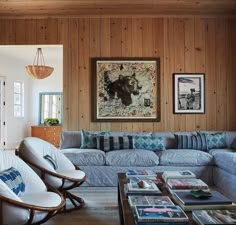 a living room with wood paneling and blue couches in front of a coffee table