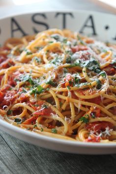 pasta with tomato sauce and parmesan cheese in a white bowl on a wooden table