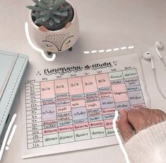 a person's hand on top of a table with a calendar and headphones