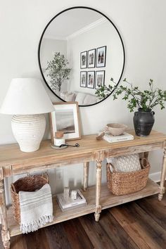 a wooden table topped with baskets under a round mirror