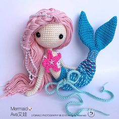 a crocheted mermaid doll sitting next to a blue and pink stuffed whale tail