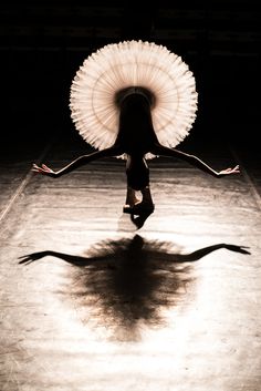 a woman is dancing in the dark with an umbrella on her head and arms behind her back