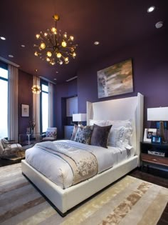 a bedroom with purple walls and white bedding in the center is lit by a chandelier