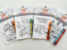 four coloring books with crayons on them sitting next to each other and two pens