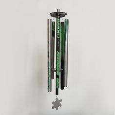 a metal wind chime with green and black items hanging from it's sides