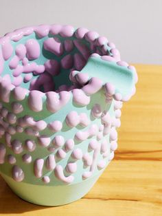 a ceramic vase sitting on top of a wooden table next to a cup filled with candy