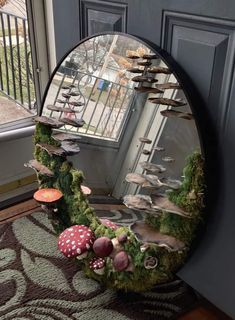 a mirror that is sitting on top of a door sill with mushrooms in it