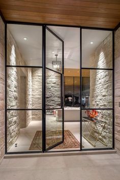 an open glass door leading into a room with stone walls and doors on both sides