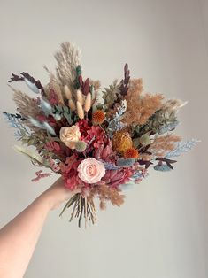 a hand holding a bouquet of flowers and feathers