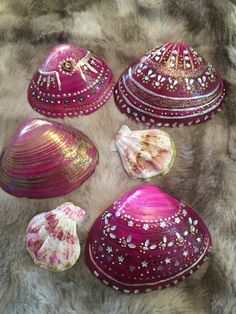 four pink and white painted shells on a fur covered surface, with one shell laying next to the other