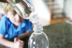 a person is pouring water into a glass bottle