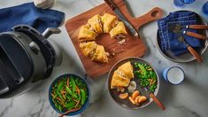 a table topped with plates and bowls filled with food next to potted green beans