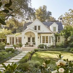 a white house surrounded by greenery and flowers