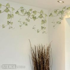 a vase filled with dry grass next to a wall mounted plant on a white wall