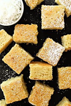 several pieces of cake sitting on top of a black surface next to a small white bowl