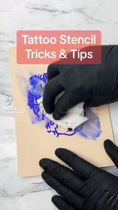 a person in black gloves is painting on a piece of paper