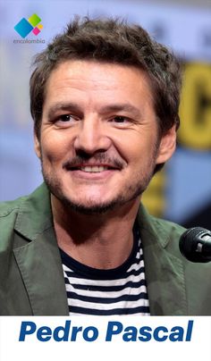 a man with a mustache smiles at the camera while wearing a green jacket and striped shirt