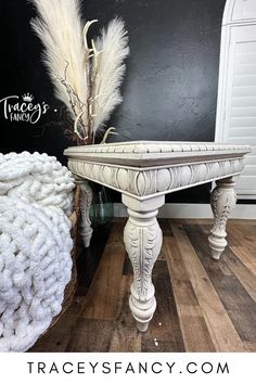 a white table sitting on top of a hard wood floor next to a black wall