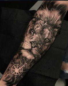 a man's arm with a lion and compass tattoo on the left side of his arm