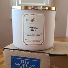 a white candle sitting on top of a cardboard box next to a blue and gold sticker