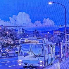 a city bus driving down the street at night with traffic lights and buildings in the background