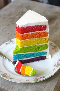 a slice of rainbow cake on a plate with a fork