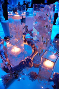 candles are lit in glass vases on a table