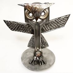 an owl sculpture is shown on a metal stand with its wings spread out and eyes wide open