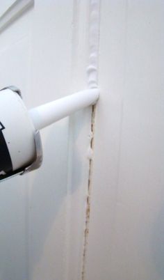 a toilet paper dispenser attached to a white door with brown stains on it