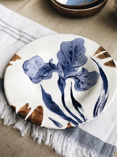 a white plate with blue flowers painted on it sitting on a table next to other plates