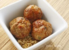 three meatballs in a white bowl on top of rice