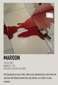 a bottle of wine sitting on top of a floor next to a red paint spatula