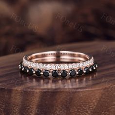 a stack of black and white stones on top of a wooden table with a diamond band