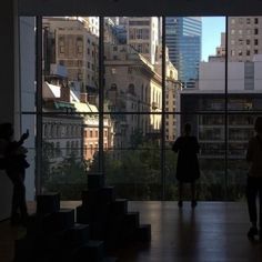 two people standing in front of large windows looking out at cityscape and skyscrapers