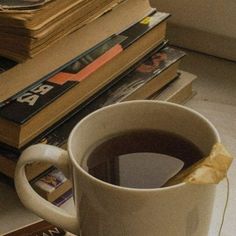 a cup of coffee sitting on top of a pile of books