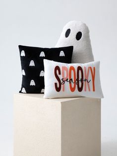 two halloween pillows sitting on top of a white block in front of a black and white pillow with the word spooky printed on it