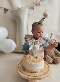 a baby is standing in front of a cake