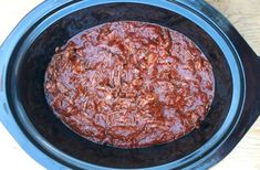 a crock pot filled with food sitting on top of a wooden table