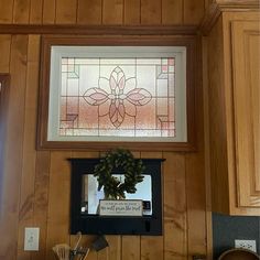 a stained glass window hanging on the side of a wooden wall above a stove top oven