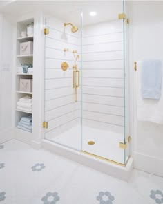 a walk in shower sitting next to a white wall with gold accents on the doors