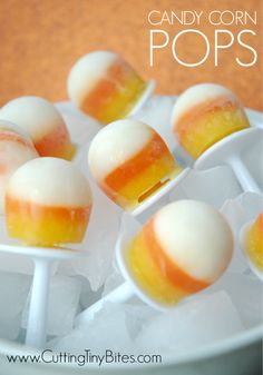 candy corn pops are sitting on top of ice in a white bowl with orange and yellow stripes