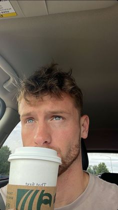 a man sitting in the back seat of a car drinking out of a coffee cup