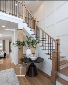 there is a vase with some plants on the table in front of the stair case